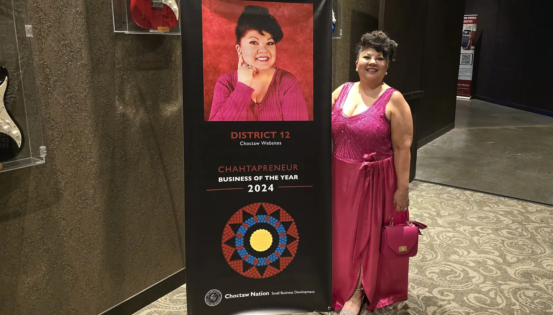 Sash Johnson standing next to a banner of herself, being named Business of the Year